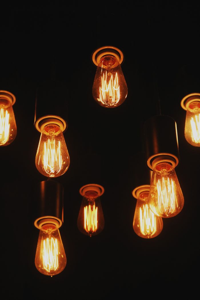 Multiple vintage Edison lightbulbs glowing warmly against a dark backdrop.